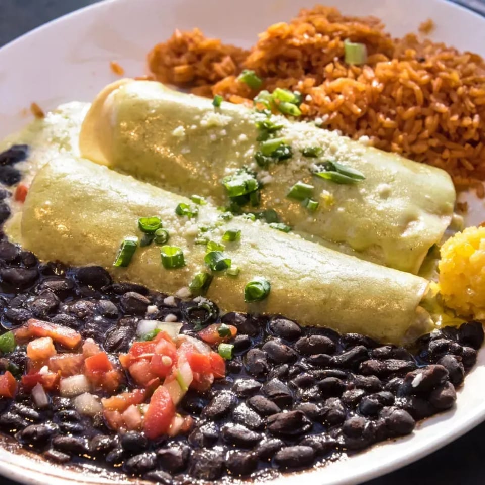 Two green enchiladas with rice, black beans, and pico de gallo on a white plate.